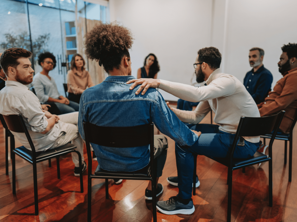 “Group of people sitting together in a recovery support meeting, symbolizing connection and shared healing.”
