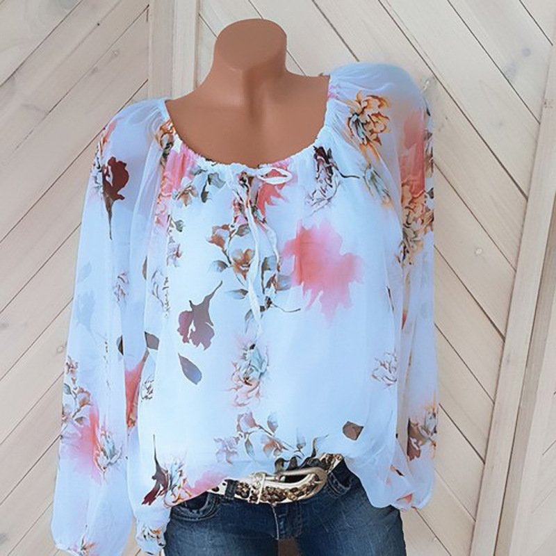 1624002717570jpg • Punkin's Patch Light blue floral sheer blouse with long sleeves on a mannequin, paired with jeans and a belt.