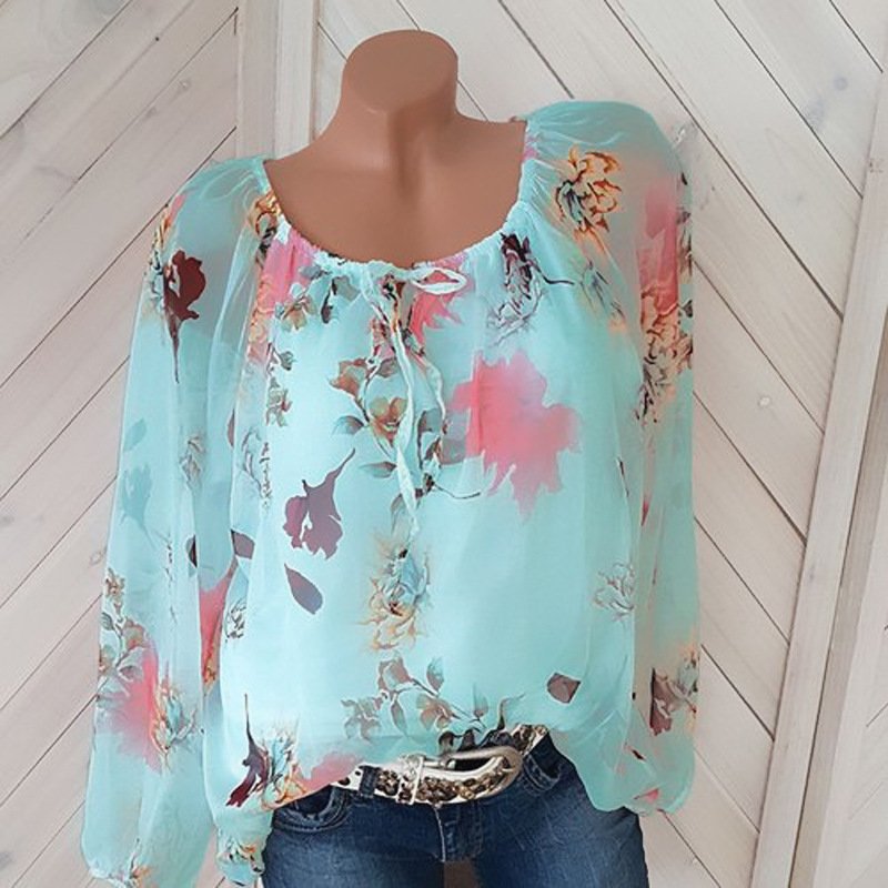 1624002717579jpg • Punkin's Patch Turquoise floral sheer blouse with a tie at the neckline displayed on a mannequin, paired with jeans and a silver belt.