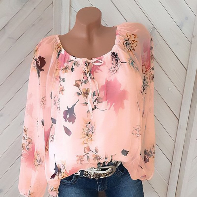 1624002717590jpg • Punkin's Patch Pink floral chiffon blouse with a gathered neckline and long puff sleeves on a mannequin, paired with jeans and a belt.