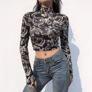 Woman wearing a black-and-white dragon-print long-sleeve crop top with a high-waisted blue jean, posing against a white wall.