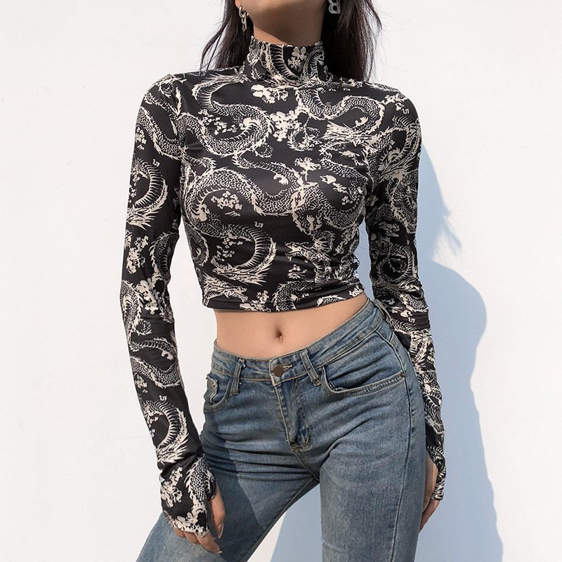 2320982399702jpg • Punkin's Patch Woman wearing a black-and-white dragon-print long-sleeve crop top with a high-waisted blue jean, posing against a white wall.