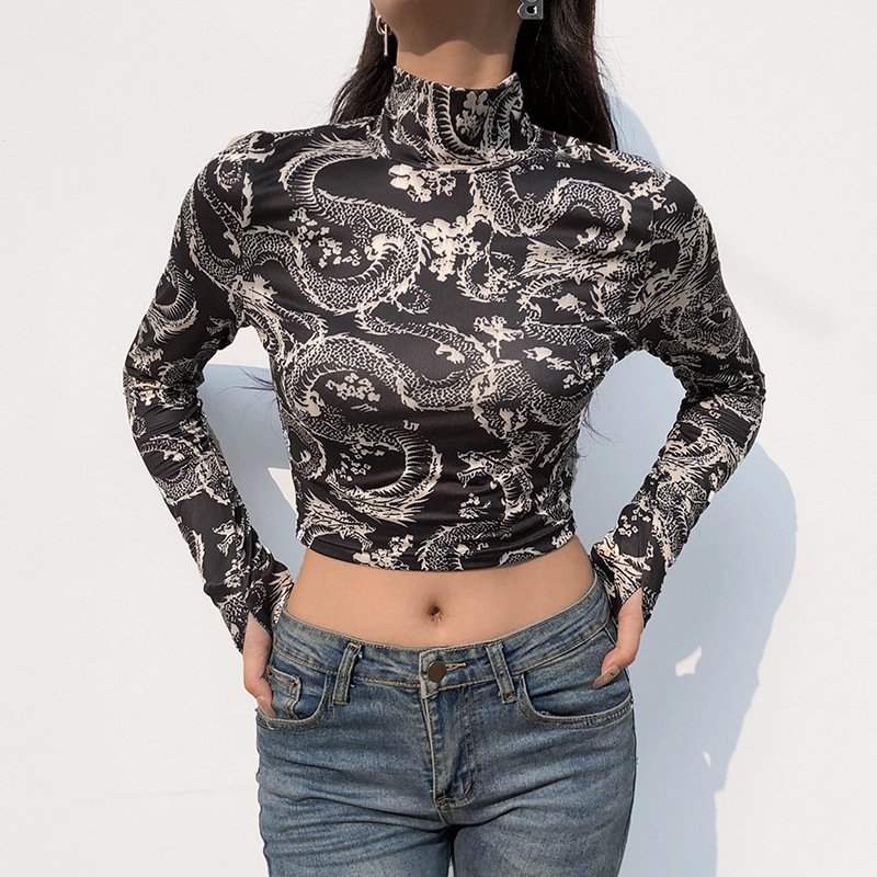 6600325986462jpg • Punkin's Patch Woman wearing a black and white long-sleeve crop top with a high neck and an intricate dragon pattern, paired with blue jeans.