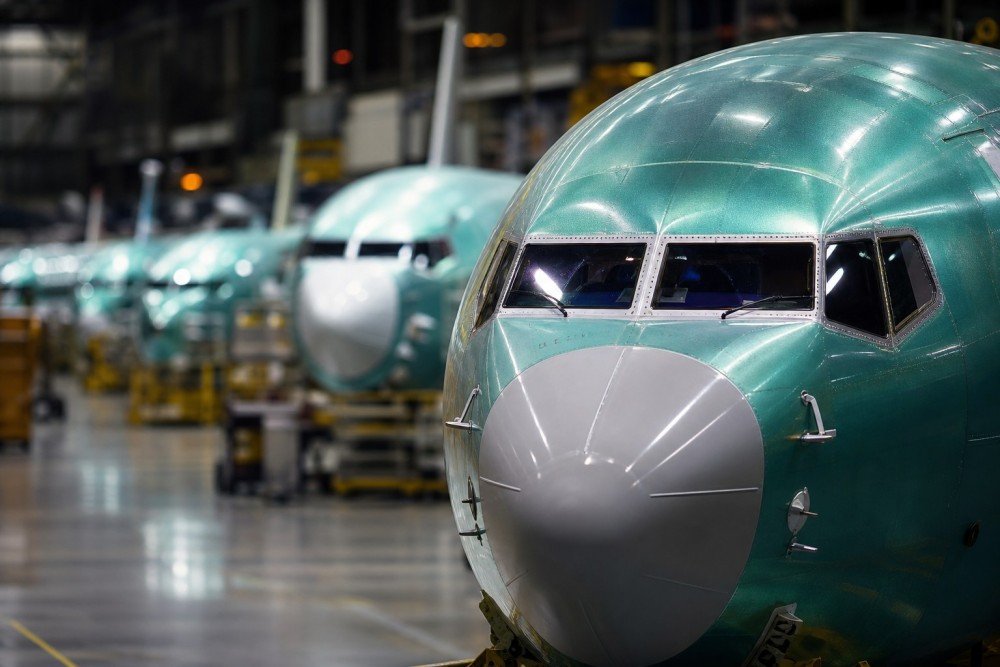 wp-header-logo-688png • Punkin's Patch Teal airplane fuselages in a factory hangar, with the closest nose in focus and other jets blurred in the background.