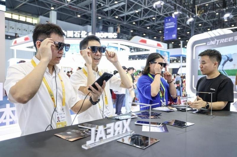 wp-header-logo-713png • Punkin's Patch Group of four expo attendees wearing sunglasses try on smart glasses at a tech booth, with a staffer demonstrating a device on the table.