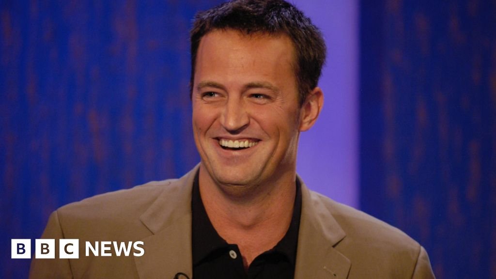 Smiling man in a light brown blazer on a BBC News set with a blue backdrop
