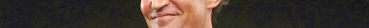 Close-up of a smiling person's lips and chin against a dark background.