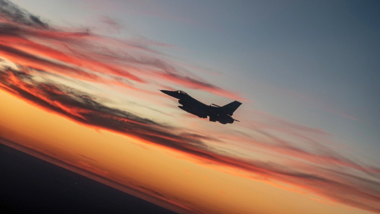 wp-header-logo-905png • Punkin's Patch Silhouette of a fighter jet in mid-flight against a colorful sunset with orange and pink clouds.