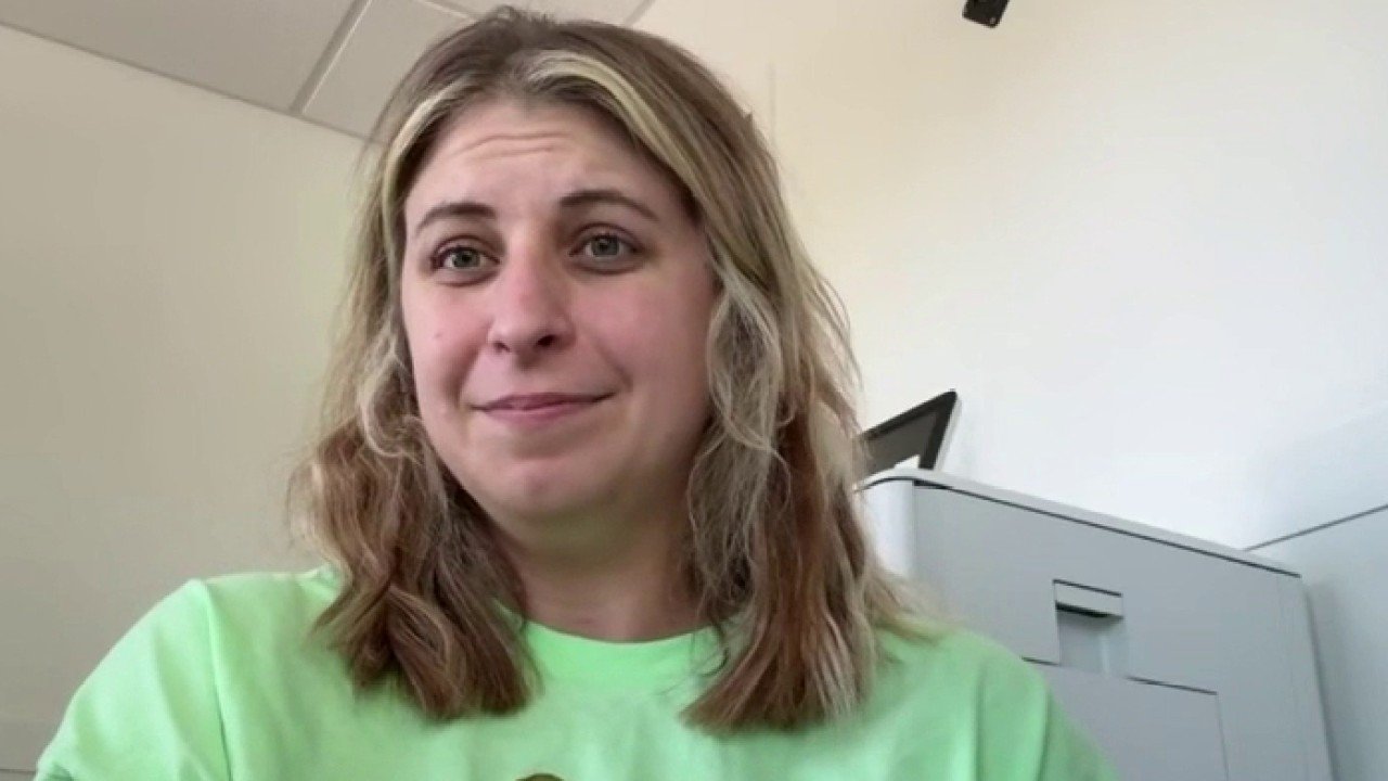 wp-header-logo-915png • Punkin's Patch Woman with shoulder-length blonde hair wearing a neon green shirt sits in an office, looking at the camera with a slight smile.
