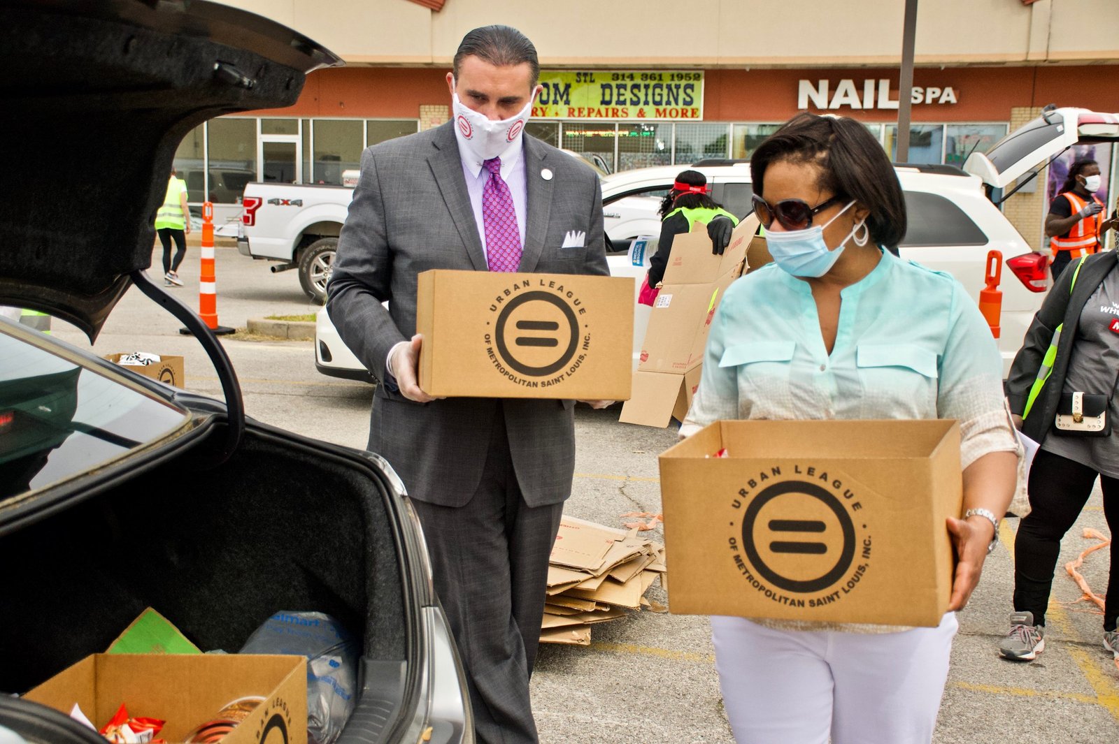 wp-header-logo-934png • Punkin's Patch People in a parking lot unload boxes from a car for a drive‑thru donation event, wearing masks and gloves.