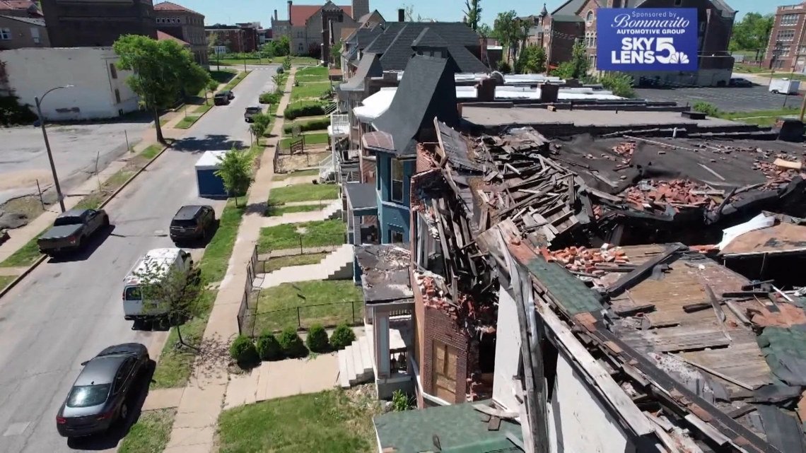 Aerial view of a row of houses with a heavily damaged, collapsed roof and rubble on one building area of the block.