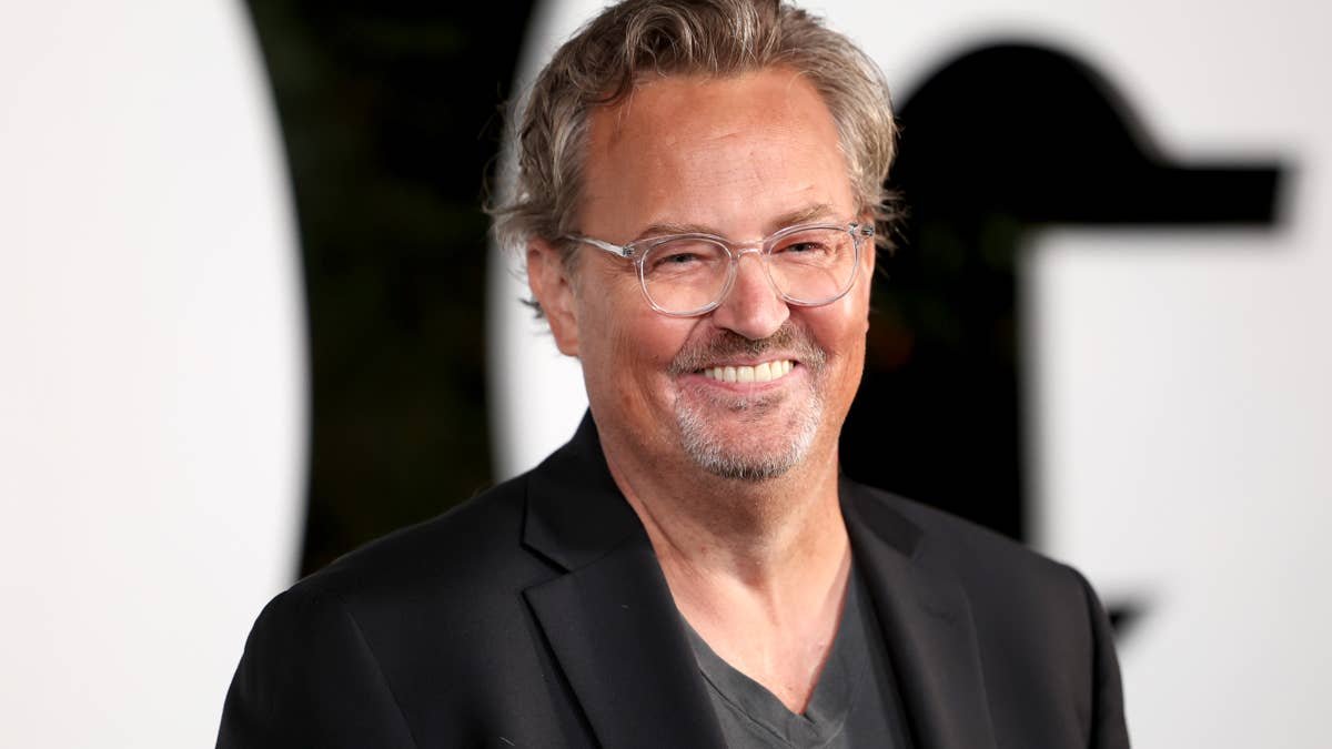 Smiling man with gray hair and clear glasses wearing a black blazer at a formal event.